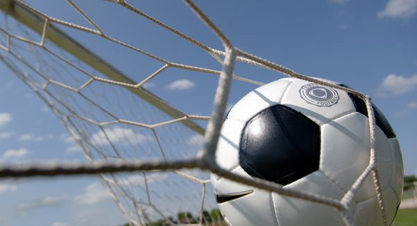 Football - soccer ball in goal against blue sky